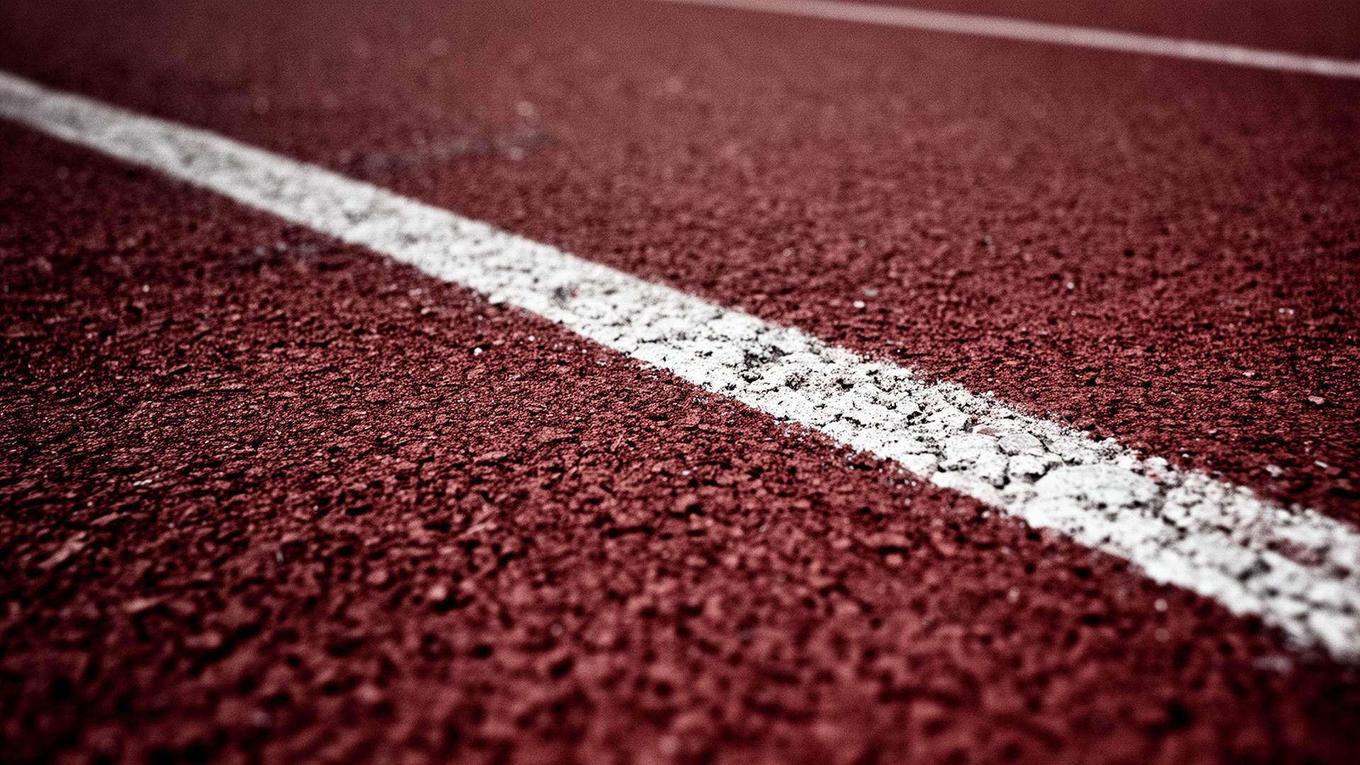 Macro texture of a weathered red athletic running track with a faded white lane line